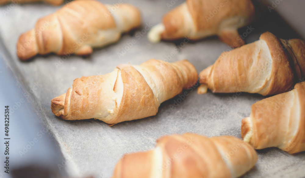 Oven-baked croissants on baking sheet. Sweet bagels baked in hot oven. The process of making curd bagels or French croissants. Oven-baked croissants on baking sheet. Sweet bagels baked in hot oven. The process of making curd bagels or French croissants.