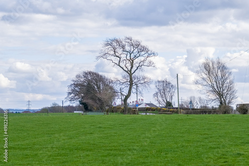 Beautiful Scottish Farmlands with farming fields and trees and hedgerows looking towards the roof tops of Perceton Row in the far distance, photo