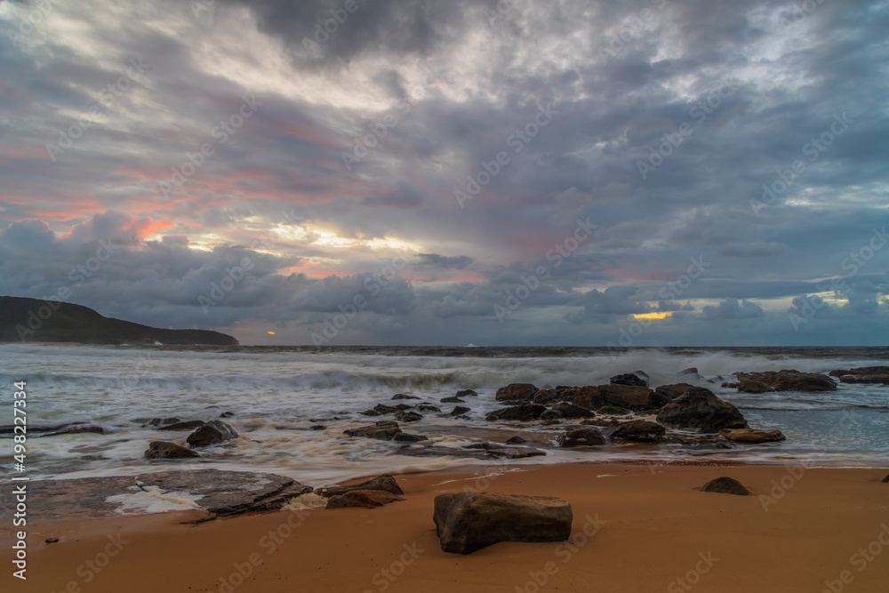 Soft sunrise seascape with rocks and rain clouds