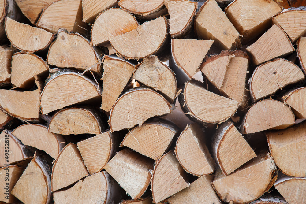 Stock of firewood for heating the house. The trees were cut down and split into firewood to be used as heating fuel in fireplaces and stoves, firewood background.