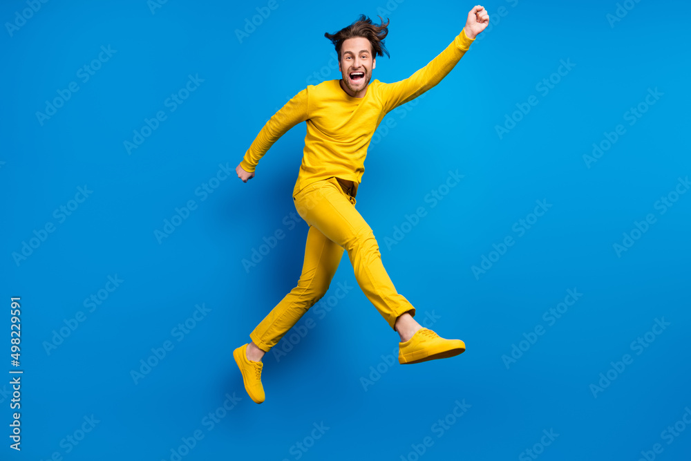 Full length body size view of attractive cheerful guy jumping having fun isolated over bright blue color background