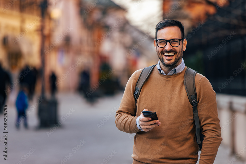 Fototapeta premium Portrait of laughing, caucasian man with backpack, getting a nice message.