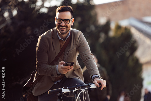 Portrait of elegant businessman, going to work by bike, using his mobile.