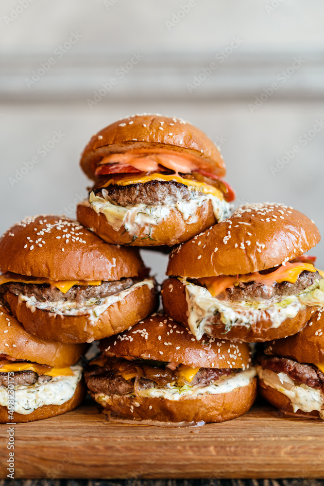 Tower of burgers with marbled beef patty, pickled cucumbers, chkdder cheese, tomato, caramelized onion, tartar sauce Tower of burgers with marbled beef patty, pickled cucumbers, chkdder cheese, tomato, caramelized onion, tartar sauce
