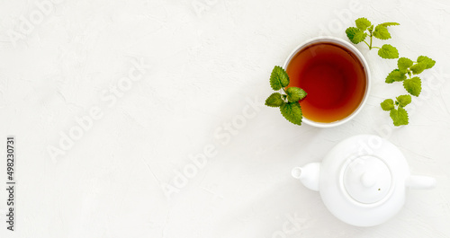 mint tea in a white cup, next to a white teapot for brewing a drink, white patchy background, flat lay, flat lay, flat lay, top view