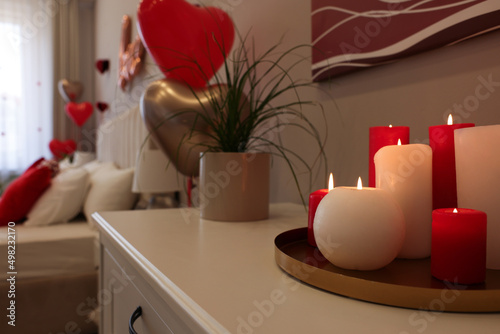 Burning candles on white table in room decorated for Valentine's Day © New Africa