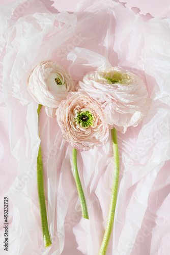 Foto Dried ranunculus flower bouquet in a plastic bag suffocating from pollution