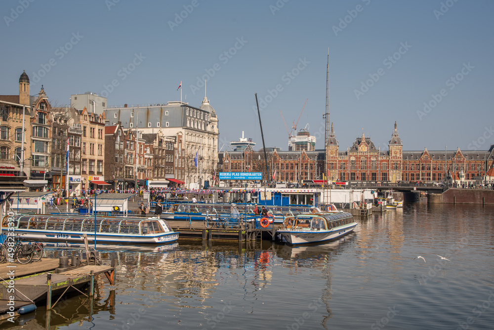 Amsterdam, Netherlands, April 2022. The Damrak with the canal boats and Central Station in Amsterdam.