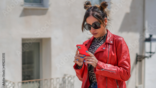 Influencer mujer joven con chaqueta roja visionando sus likes antes de una sesión de fotos photo