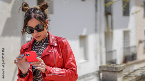 Influencer mujer joven con chaqueta roja visionando sus likes antes de una sesión de fotos photo