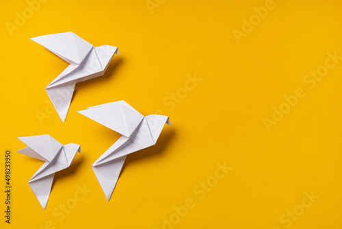 White origami doves as a symbol of faith, hope and peace on a yellow background