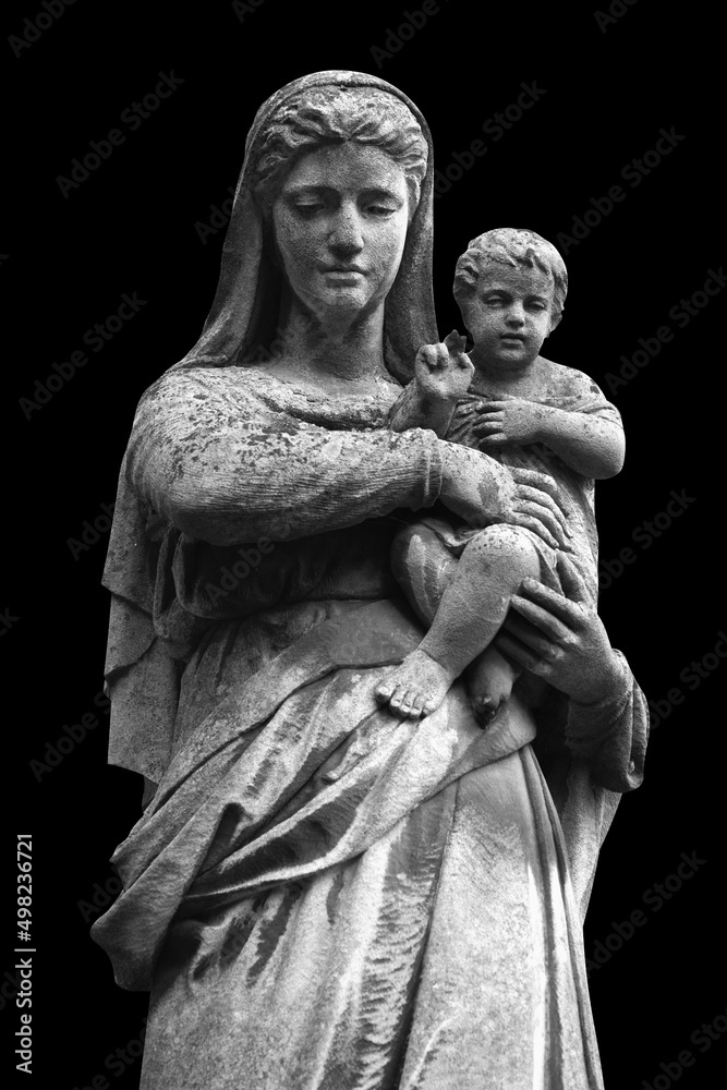 Virgin Mary with the baby Jesus Christ. An ancient statue isolated on  black background.