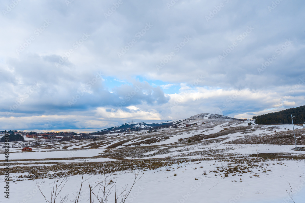 Snow fell on the dry grass. on mountain with big cloudy sky