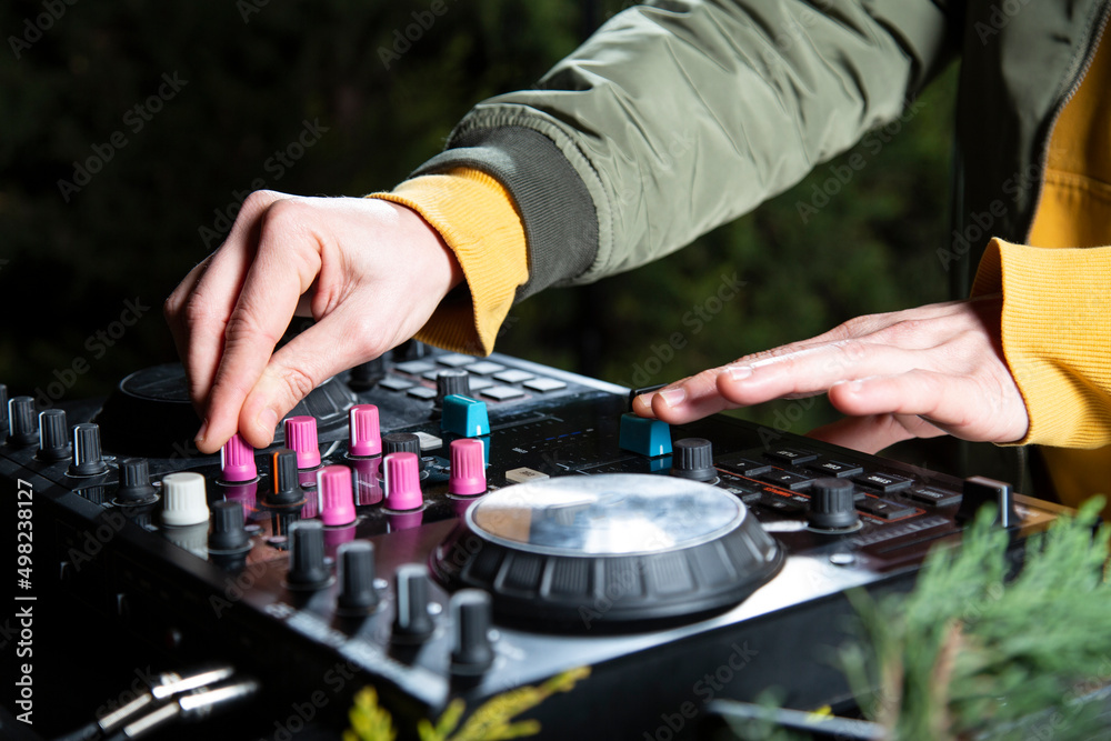 manos DJ mezclando musica en una mesa de mezclas fiesta en el bosque por la noche close-up, rave party manos DJ mezclando musica en una mesa de mezclas fiesta en el bosque por la noche close-up, rave party