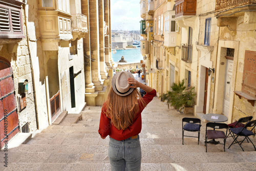 Obraz na płótnie Holidays in Malta. Back view of traveler woman descends stairs in the historic city of Valletta, UNESCO World Heritage, Malta. w salonie