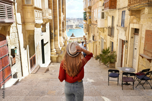 Holidays in Malta. Back view of traveler woman descends stairs in the historic city of Valletta, UNESCO World Heritage, Malta.