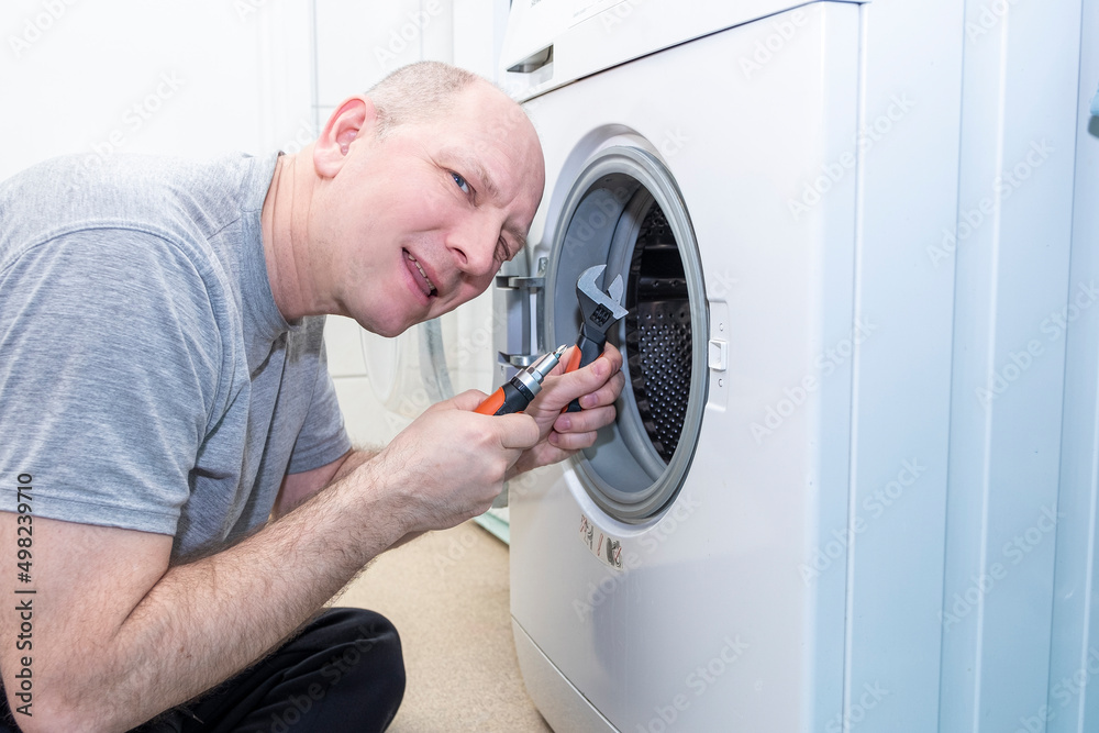 Obraz premium Caucasian man repairing a washing machine, repair and maintenance.