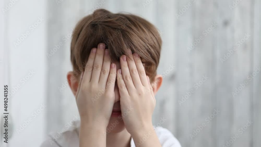 Boy toddler plays hide and seek with his hands, closes and opens his eyes with his hands. Child playing peek-bo his eyes. Fun games with kids at home. Kid fools with hides Boy toddler plays hide and seek with his hands, closes and opens his eyes with his hands. Child playing peek-bo his eyes. Fun games with kids at home. Kid fools with hides