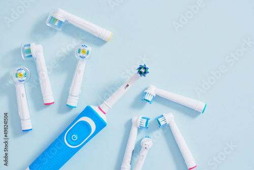 electric toothbrush and multi-colored replaceable nozzles on blue background