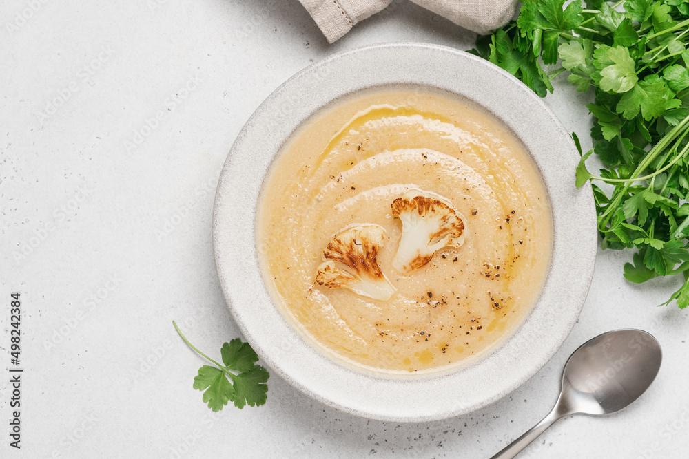 Cauliflower soup in bowl on light background. Vegetable Vegan cream soup with parsley Cauliflower soup in bowl on light background. Vegetable Vegan cream soup with parsley