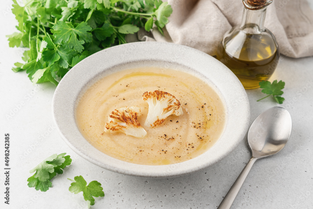 Cauliflower soup in bowl on light background. Vegetable Vegan cream soup with parsley Cauliflower soup in bowl on light background. Vegetable Vegan cream soup with parsley
