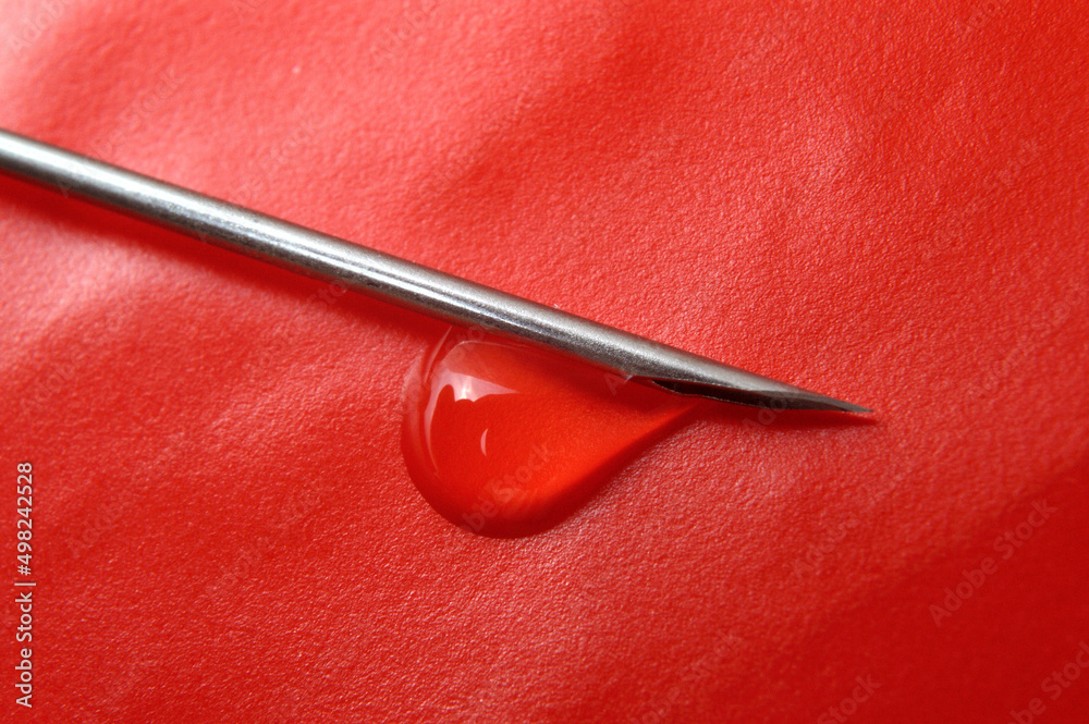 Syringe needle and a drop of a transparent substance. close-up