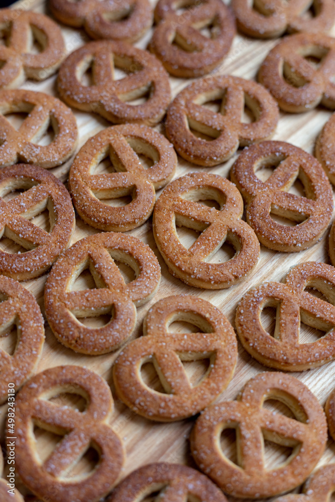 Pretzels sprinkled with sugar lie on a wooden surface