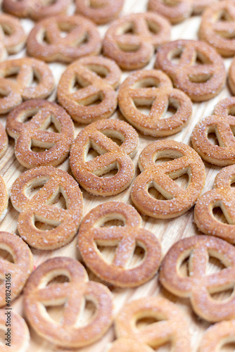 Pretzels sprinkled with sugar lie on a wooden surface