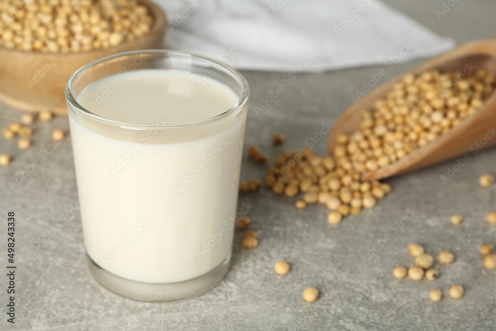 Glass with fresh soy milk and grains on grey table Glass with fresh soy milk and grains on grey table