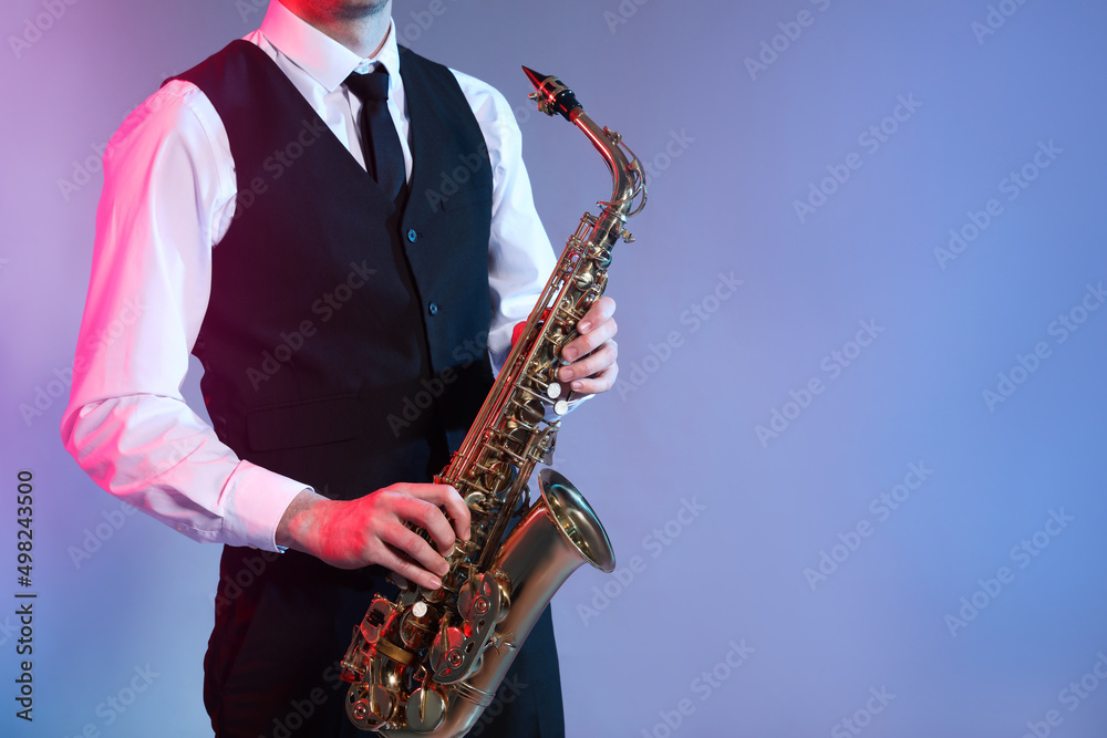 Fototapeta premium Man in elegant outfit playing saxophone on color background, closeup. Space for text