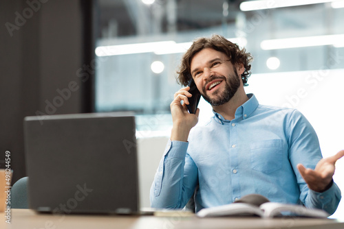 Smiling business man working and talking on cellphone at office