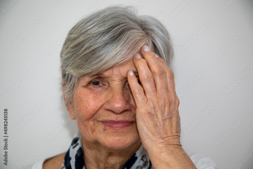 Close Up Of Middle Aged Woman Covering Her Face With One Hand While Looking At The Camera. Close Up Of Middle Aged Woman Covering Her Face With One Hand While Looking At The Camera.