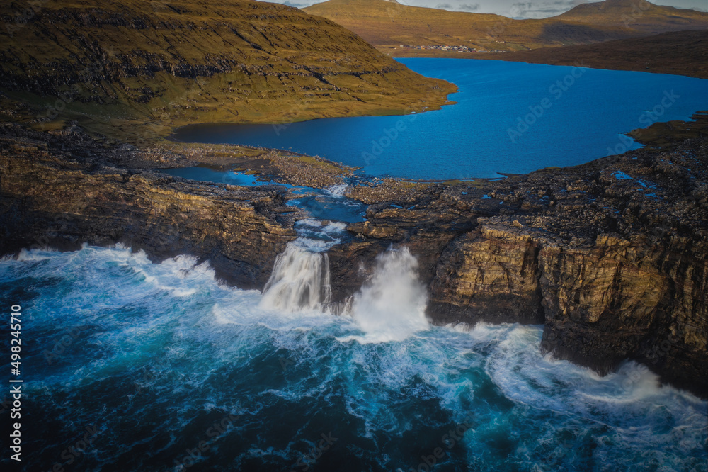 Panoramic view from flying drone of Bosdalafossur waterfall. Amazing autumn scene of Sorvagsvatn lake, Vagar, Faroe Islands, Denmark, Europe. Beauty of nature concept background. November 2021