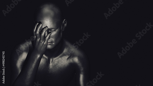 A male figure with one hand covering his face and an expression of anguish on a dark background. 3d illustration.