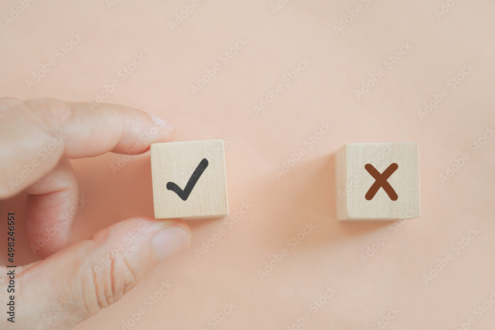 human's hand choose wooden block with true sign on sweet orange background for correcting, solving specific problem, business strategy, leadership concept human's hand choose wooden block with true sign on sweet orange background for correcting, solving specific problem, business strategy, leadership concept