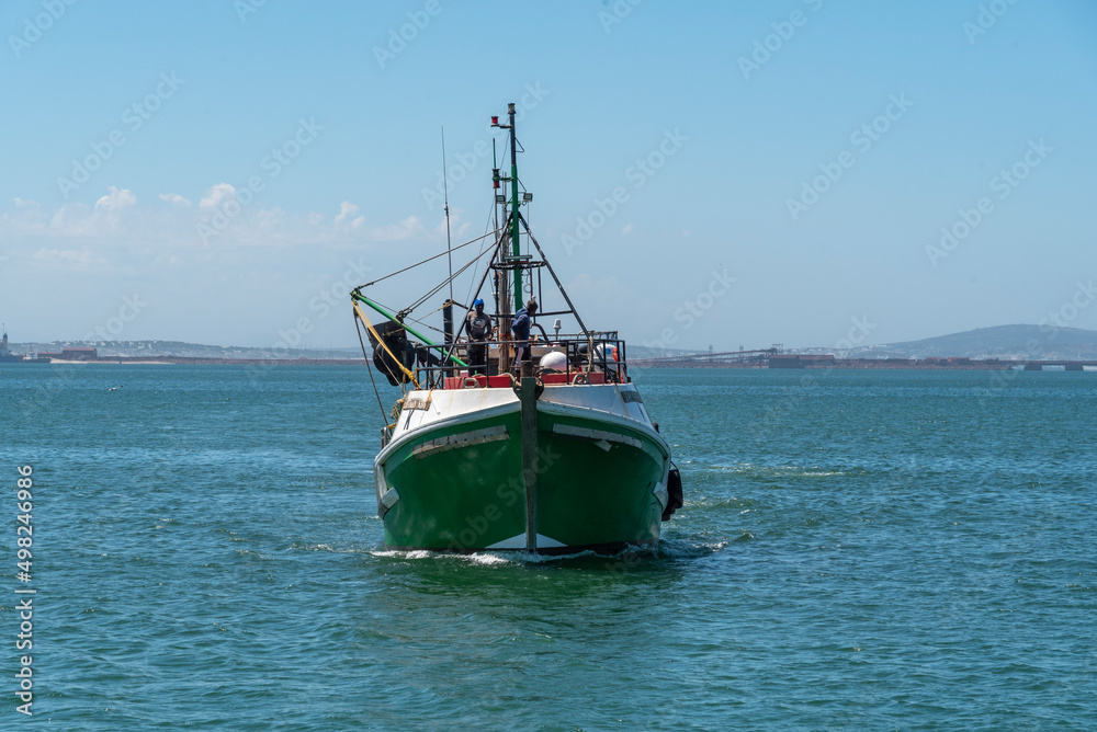 Saldanha Bay, West Coast, South Africa. 2022. Fishing boat approaching Saldanha. Two crew men tying ropes on foredeck.