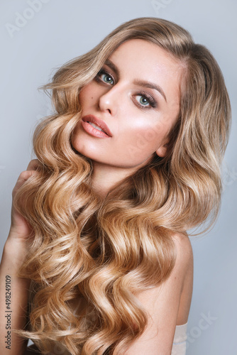 Blond woman with voluminous, shiny and curly hairstyle.Flying hair. Professional Make-up