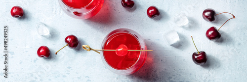 Cocktail garnished with cherry panorama, fresh cranberry juice with ice on a dark background, two glasses, a flat lay, shot from the top