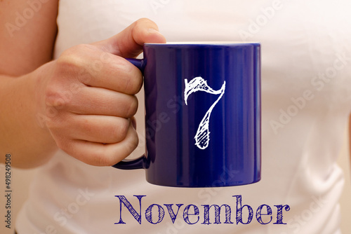 The inscription on the blue cup 7 november. Cup in female hand, business concept