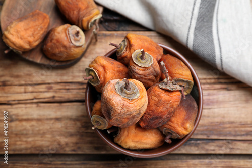 Bowl with tasty dried persimmon fruits on wooden table, flat lay