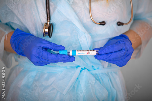 a medical worker holds in his hands a test tube with a positive test result for a covid, close-up.