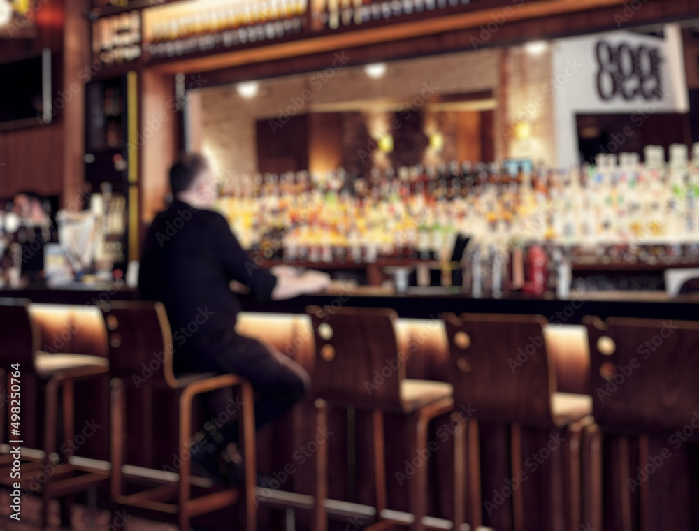 Pub interior blurry defocused background with a man sitting at the bar. Pub interior blurry defocused background with a man sitting at the bar.