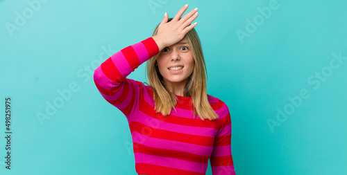 young pretty blonde woman raising palm to forehead thinking oops, after making a stupid mistake or remembering, feeling dumb