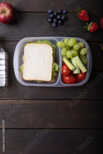 Overhead view of healthy food in lunch box on wooden table, copy space