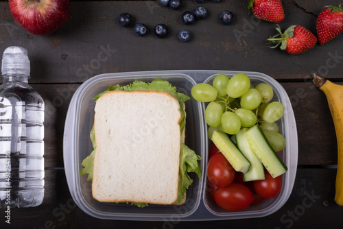 Overhead view of healthy food in lunch box by water bottle on table, copy space