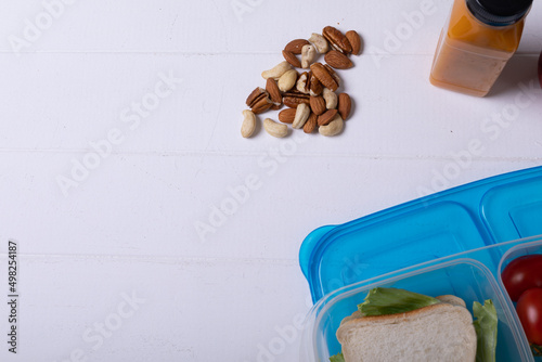 Overhead view of healthy food and tiffin box by juice bottle over white background, copy space
