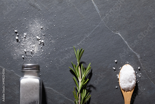 Directly above shot of salt shaker with rosemary and spoon on table