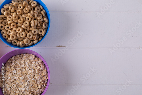 Close-up of ring shaped breakfast cereal and oatmeal in bowls on table with blank space