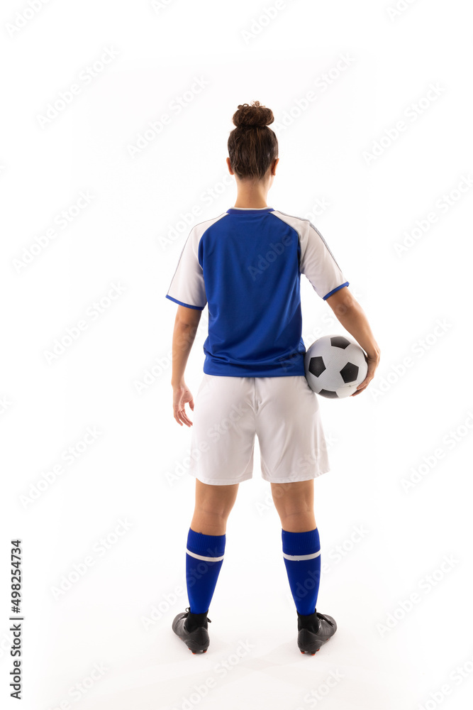 Full length rear view of biracial young female soccer player holding ball against white background