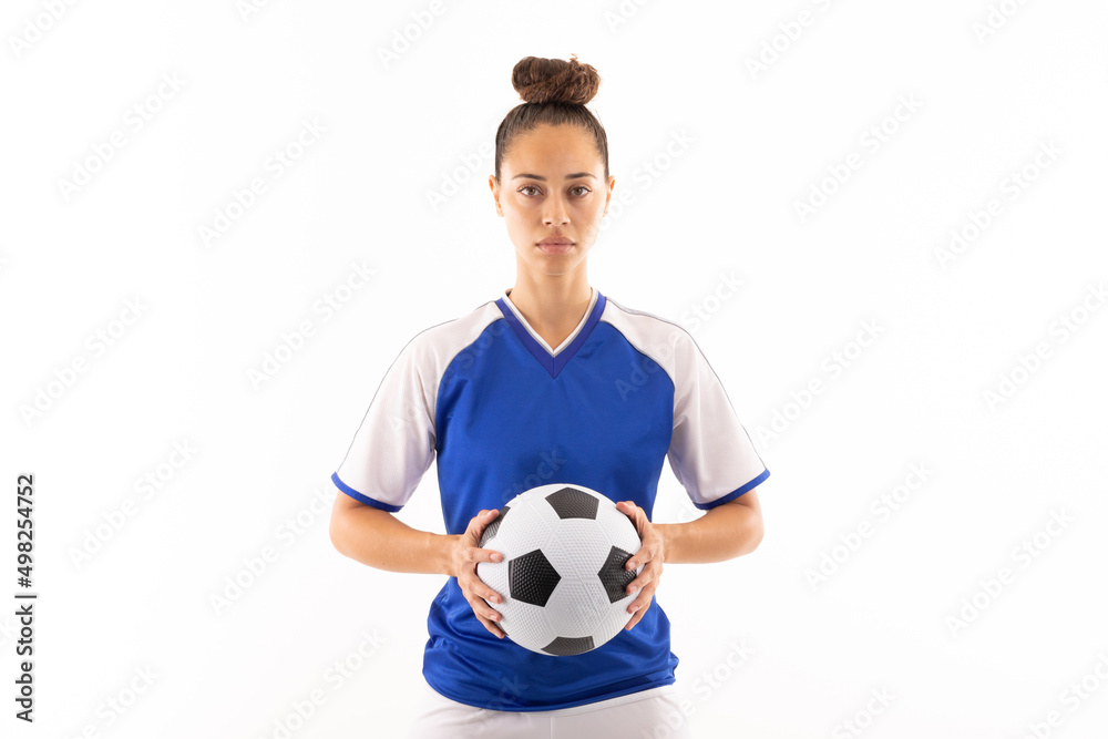 Portrait of biracial young female player holding soccer ball while standing against white background Portrait of biracial young female player holding soccer ball while standing against white background